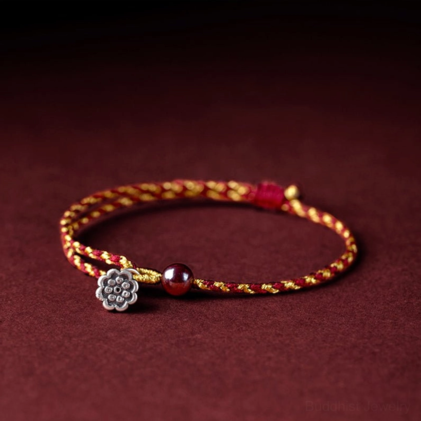 Handcrafted Buddhist string bracelet with silver lotus charm and mixed beads on burgundy background