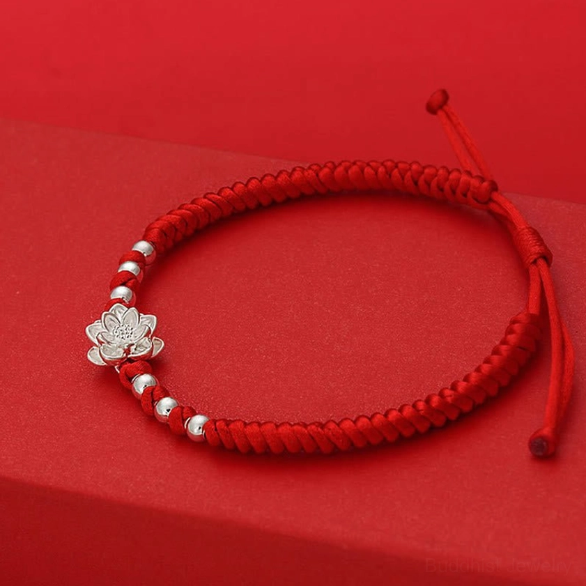 Right side view of sterling silver lotus charm on red protective string bracelet