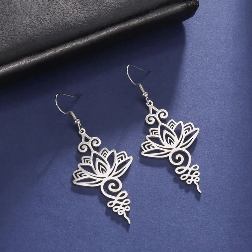 Silver hollow lotus flower earrings with curved scroll ornament detail and dark background