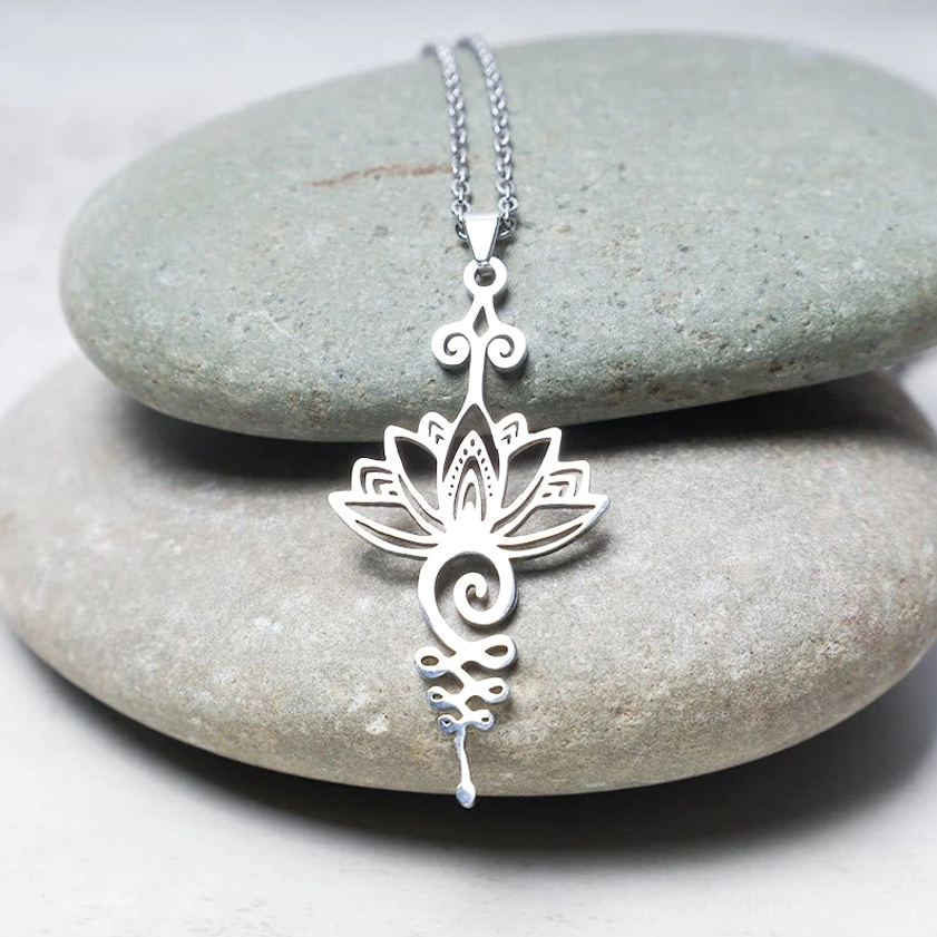Silver titanium steel lotus unalome necklace overhead view with blue accent stone on grey crystal, showcasing delicate hollow pattern