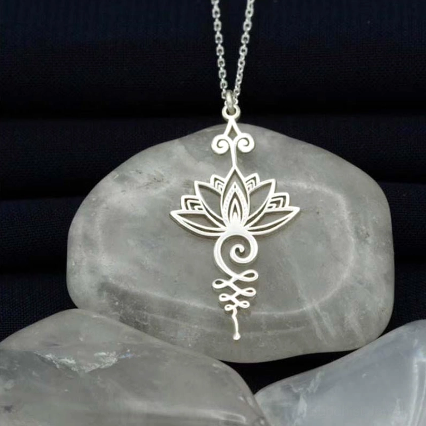 Silver lotus unalome pendant necklace with hollow carved design on dark fabric background, showing intricate spiritual Buddhist symbol