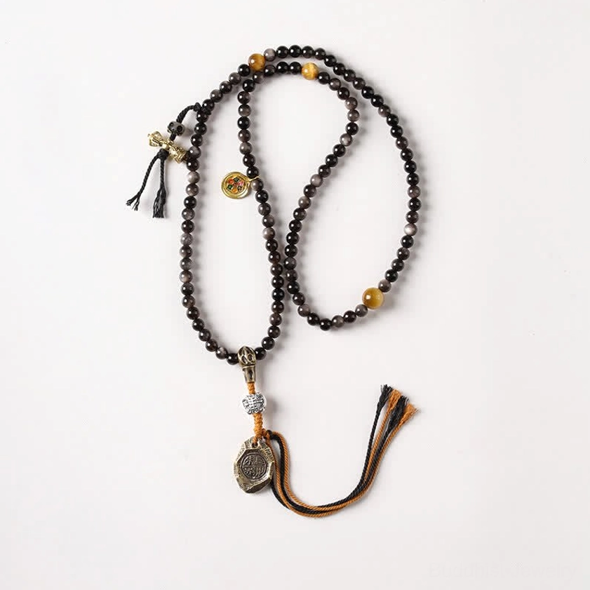 Long Silver Sheen Obsidian mala necklace with Garuda metal pendant and brown tassel featuring golden accent beads