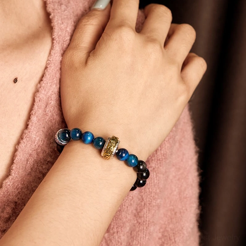 Buddhist crystal bracelet with Silver Sheen Obsidian and Blue Tiger Eye beads worn on left wrist, front view with gold-plated metal accents
