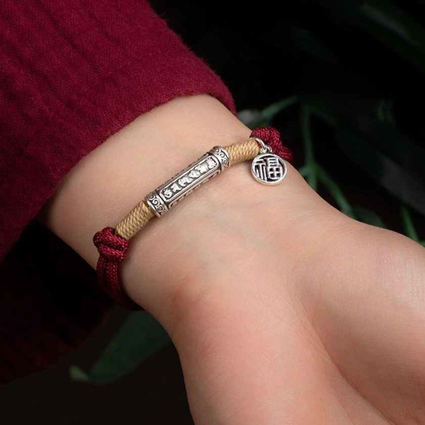 Wearing sterling silver Om Mani Padme Hum bracelet with Fu charm on wrist close-up daily wear