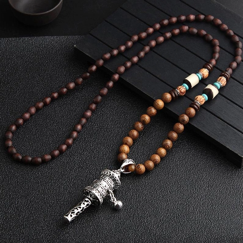 Silver prayer wheel pendant Buddhist mala necklace with wenge wood beads and white spacer beads on dark wooden background