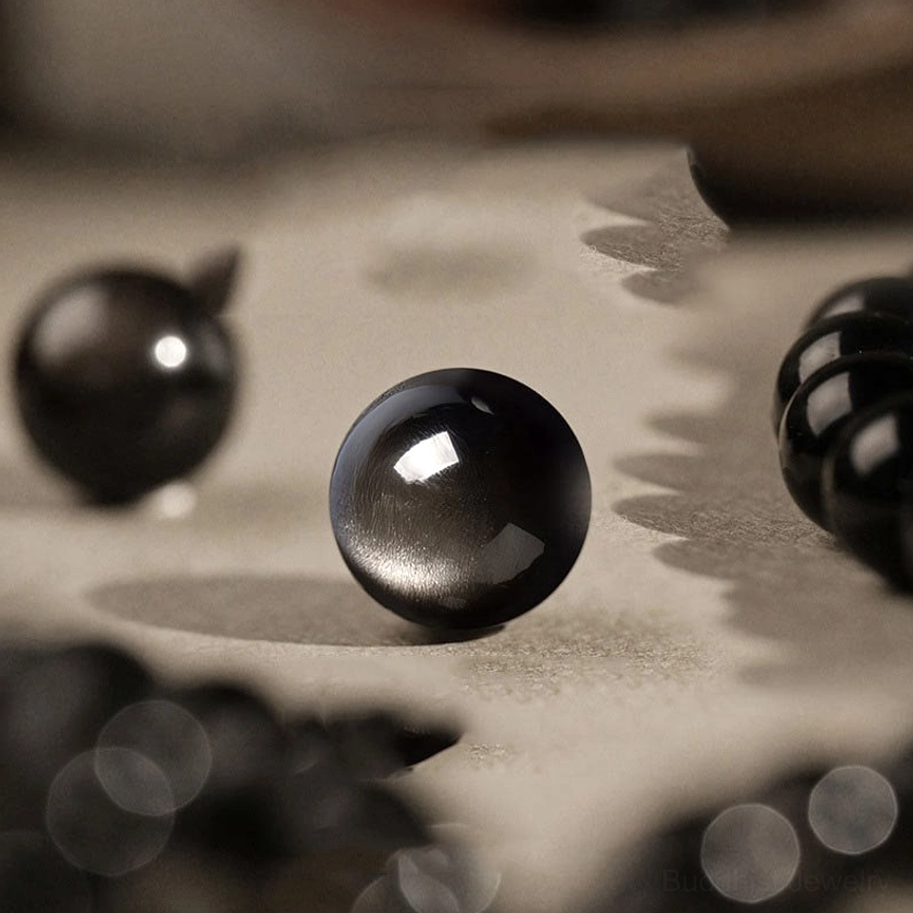 Macro close-up of polished Silver Sheen Obsidian beads showing distinctive glossy finish and authentic silver luster texture