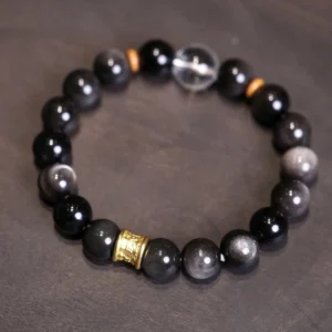 Silver Sheen Obsidian Om Mani Padme Hum Buddhist bracelet with white crystal and gold accents on dark background
