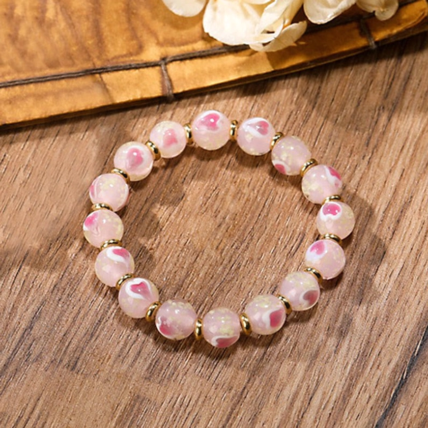 Simple pink luminous glass bead Buddhist bracelet without charms in close-up oblique view with solid pink beads and gold spacer beads