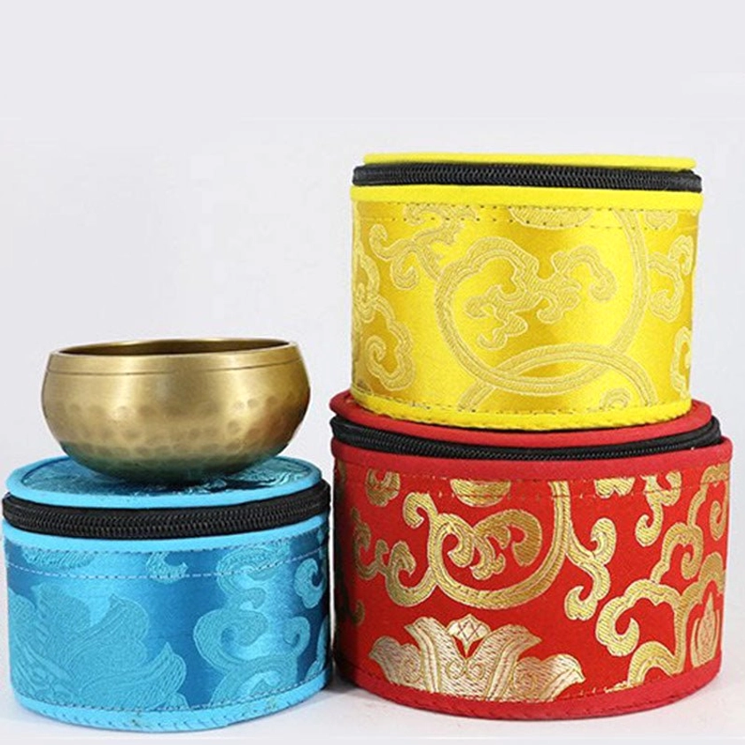 Stacked singing bowl storage pouches in multiple colors with brass bowl placement