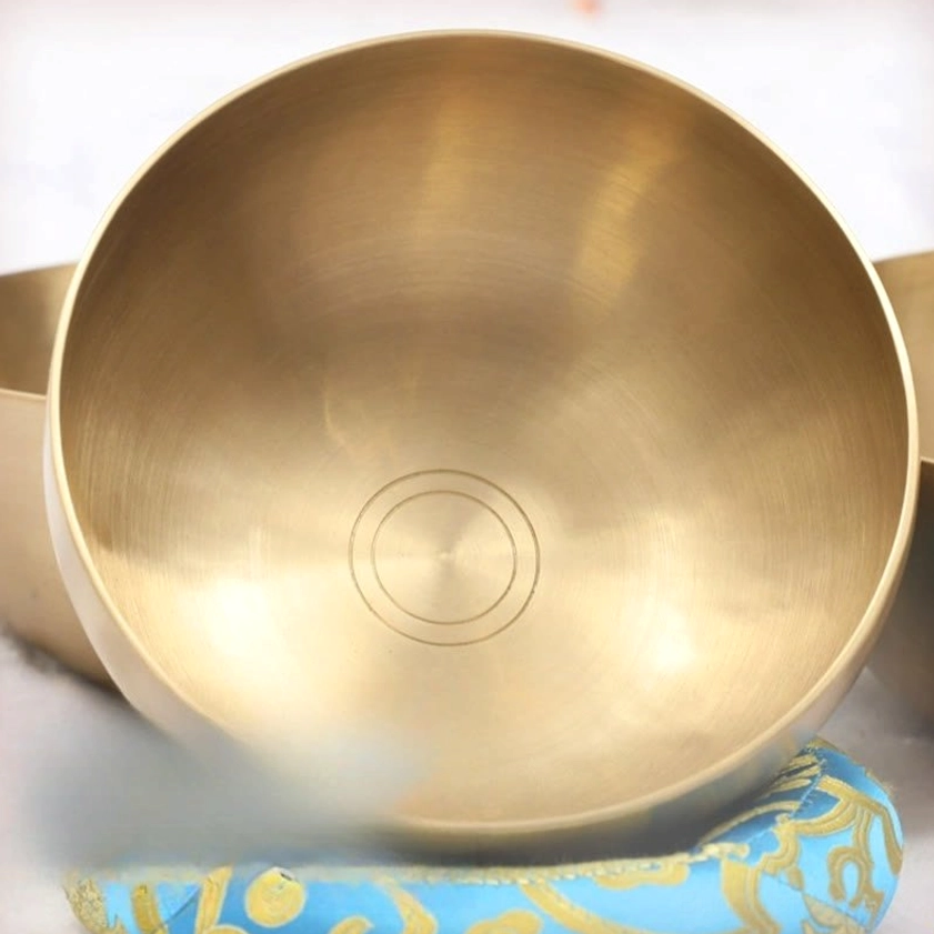 Singing bowl bottom view close-up showing polished golden brass interior with concentric circle marks from handcrafting