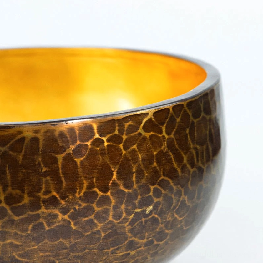 Close-up detail of singing bowl hammered crackle bronze exterior and golden inner rim surface texture