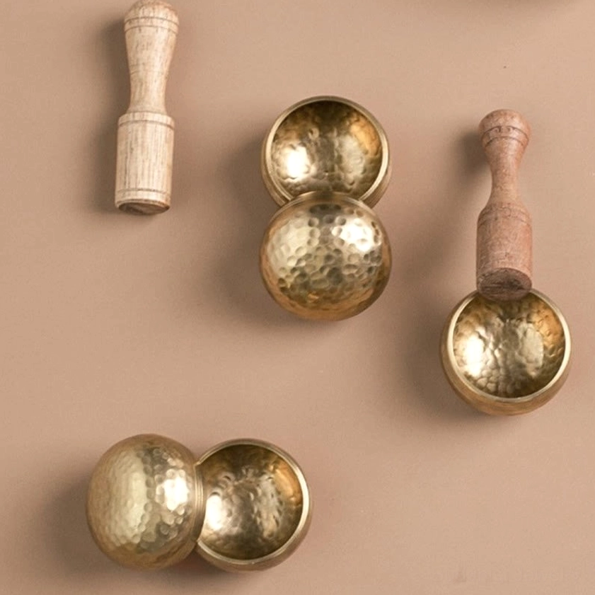 Collection of mini brass singing bowls with dual-tone wooden strikers for sound healing therapy