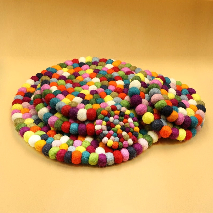 Top-down flat view of felted wool meditation cushion with densely clustered rainbow pom-poms
