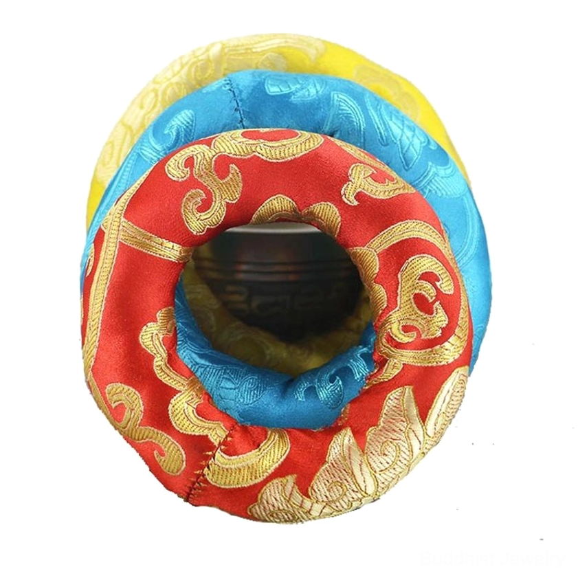Detailed close-up of red Buddhist singing bowl cushion with bright golden scroll pattern embroidery highlighting handmade textile work