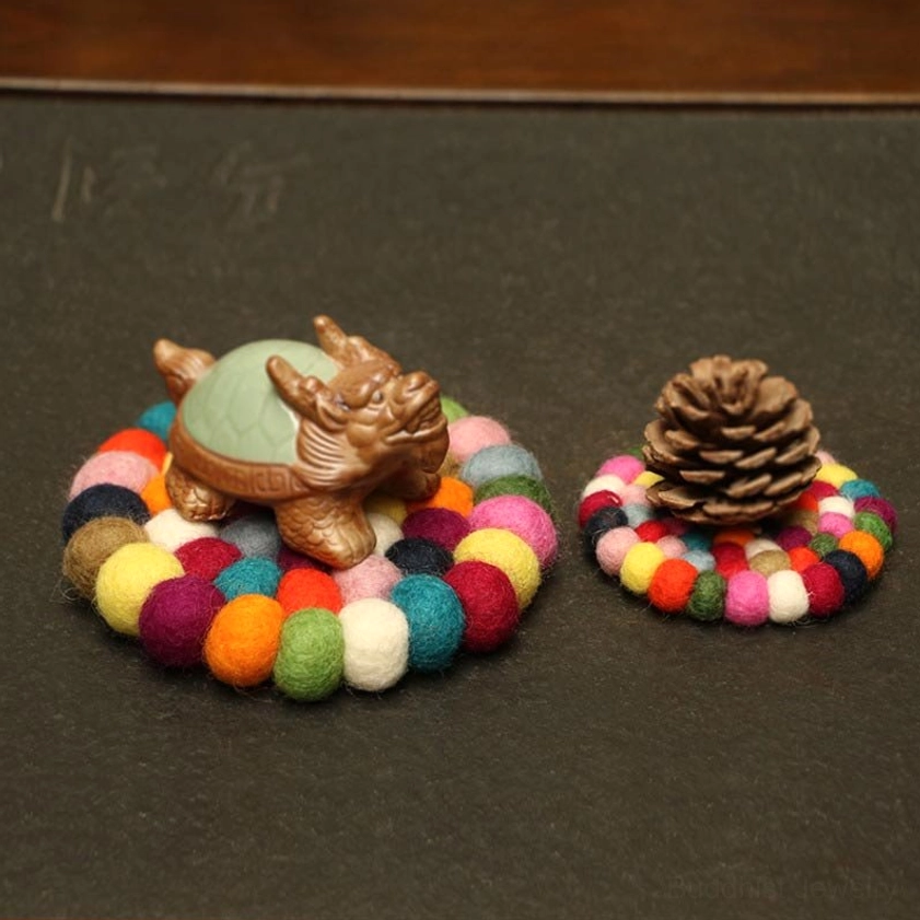 Multiple sizes of felted wool singing bowl cushions displayed with Buddhist decorative ornaments