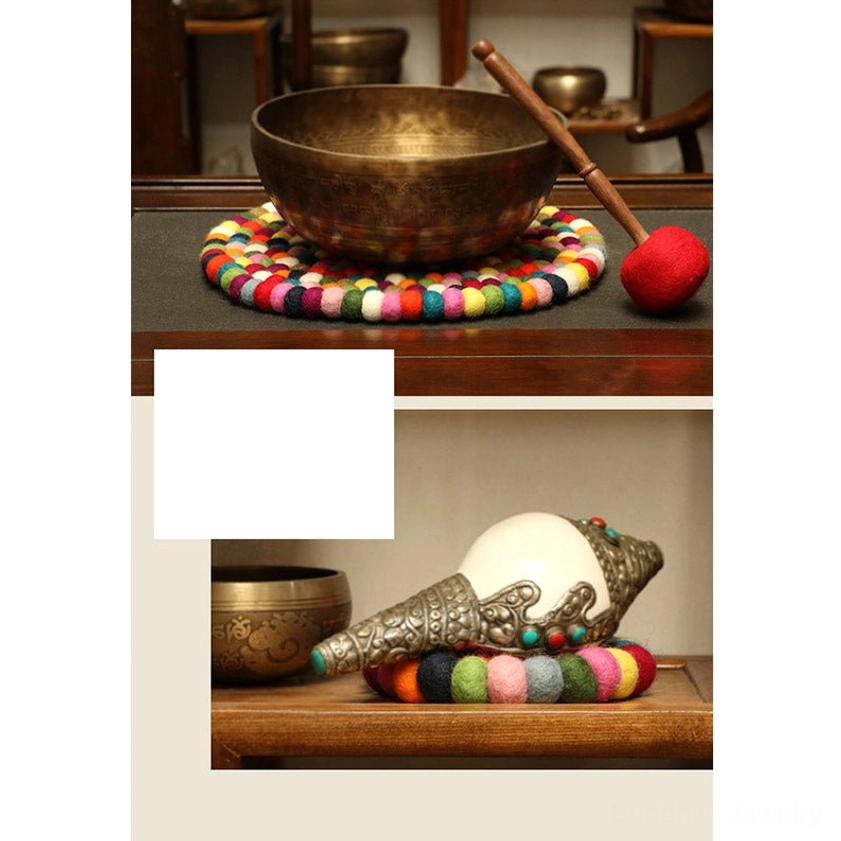 Handcrafted singing bowl with felted wool cushion and Buddhist craft ornaments on wooden shelf