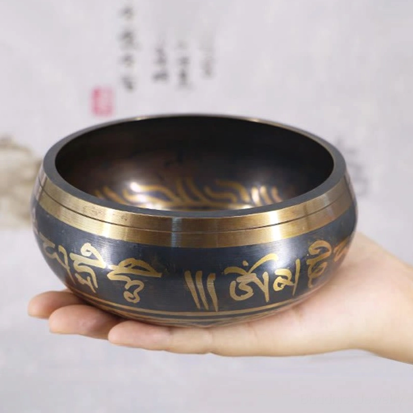 Buddhist singing bowl Om Mani Padme Hum mantra close-up detail showing intricate golden Sanskrit engraving and craftsmanship