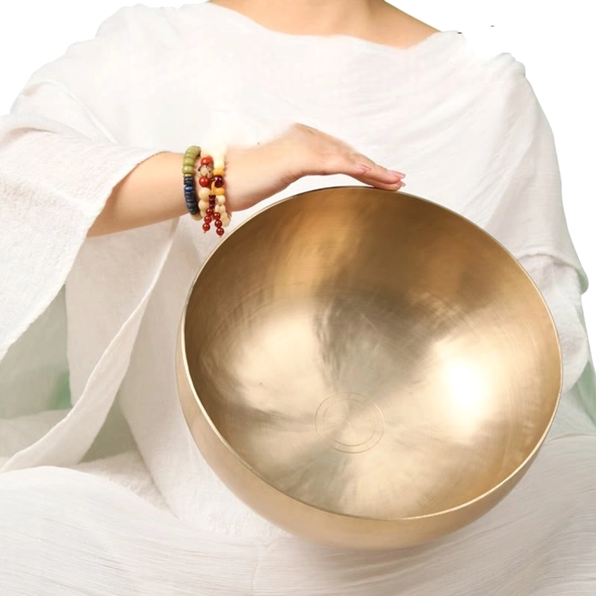 Singing bowl played with wooden striker showing proper circular technique for creating sustained healing tones