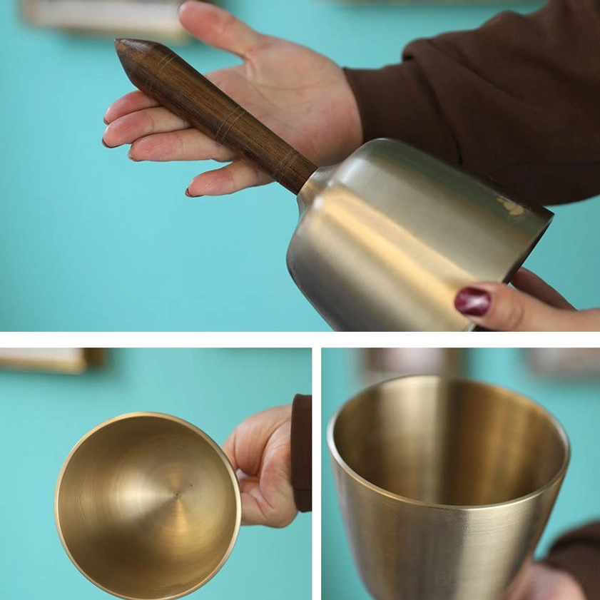 Side profile view of handcrafted copper singing bowl with curved metal body and wooden grip handle