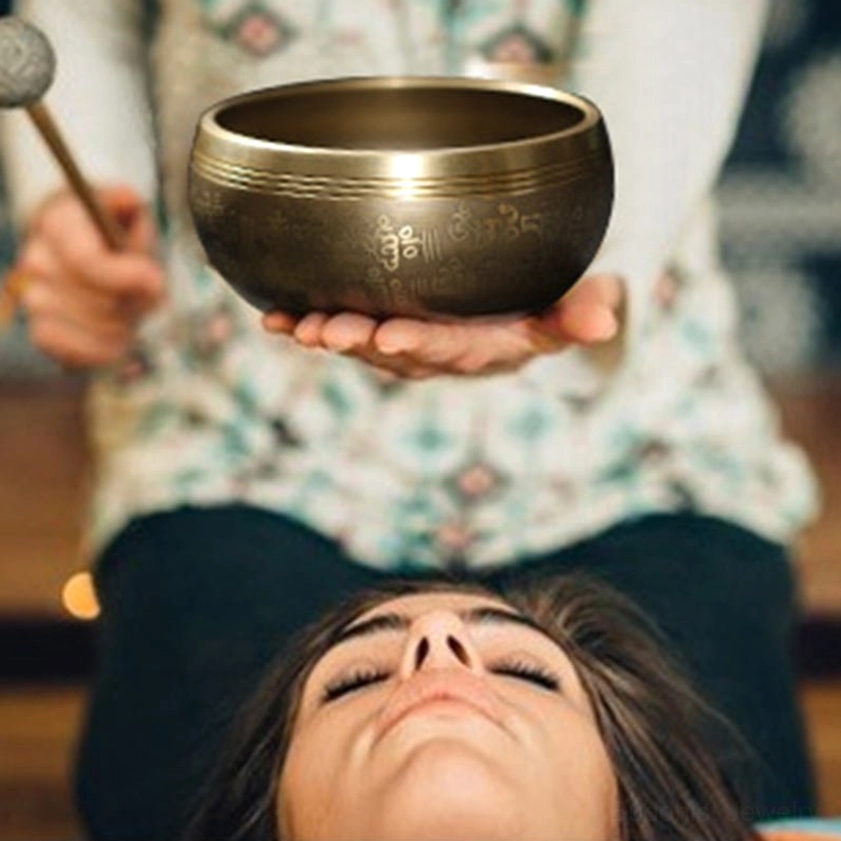 Buddhist copper singing bowl held above person in healing therapy session demonstrating sound healing vibrations