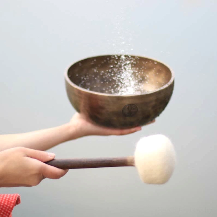 Singing bowl sound vibration demonstration with water droplets and wooden striker