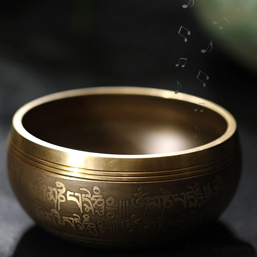 Buddhist singing bowl with engraved script and musical notes displayed with wooden striker mallet