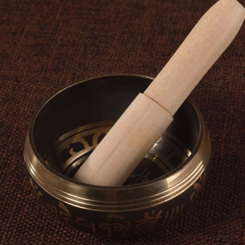 Wooden mallet resting inside handcrafted Buddhist singing bowl, positioned for meditation play