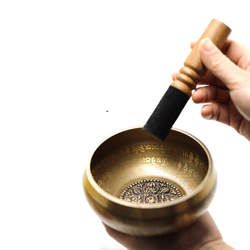 Demonstration of singing bowl playing technique using rubber-tipped wooden mallet striking the rim of handcrafted brass bowl