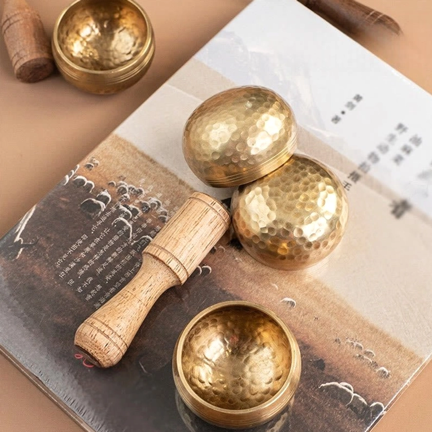 Buddhist singing bowls and strikers arranged on table with spiritual books for mindfulness practice