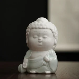 Handcrafted ceramic sitting Buddha incense burner with white body and celadon glazed robes, displayed on wooden desk - front view close-up