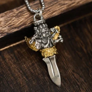 Six-armed vajra copper necklace pendant with antique silver and gold finish, displayed on dark wooden surface showing intricate carved deity design and sharp blade detail
