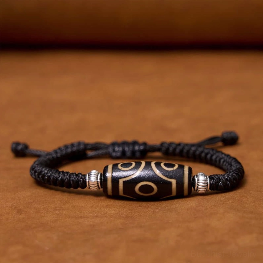 Six-eye dzi bead bracelet flat lay front view on brown background with complete design visible