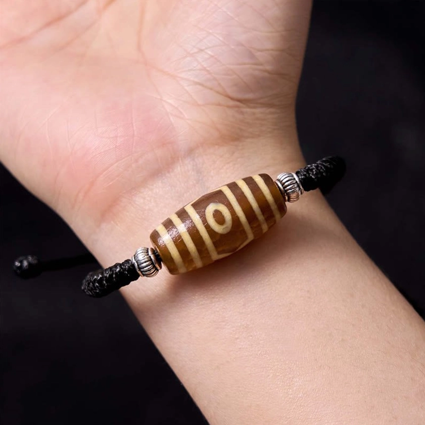 Six-eye dzi bead bracelet side angle displaying intricate six-eye motif with silver decorative accents