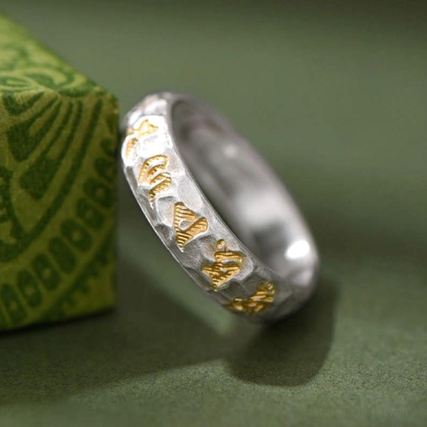 Six-syllable mantra ring oblique view showing dual-tone finish and embossed gold Sanskrit engraving