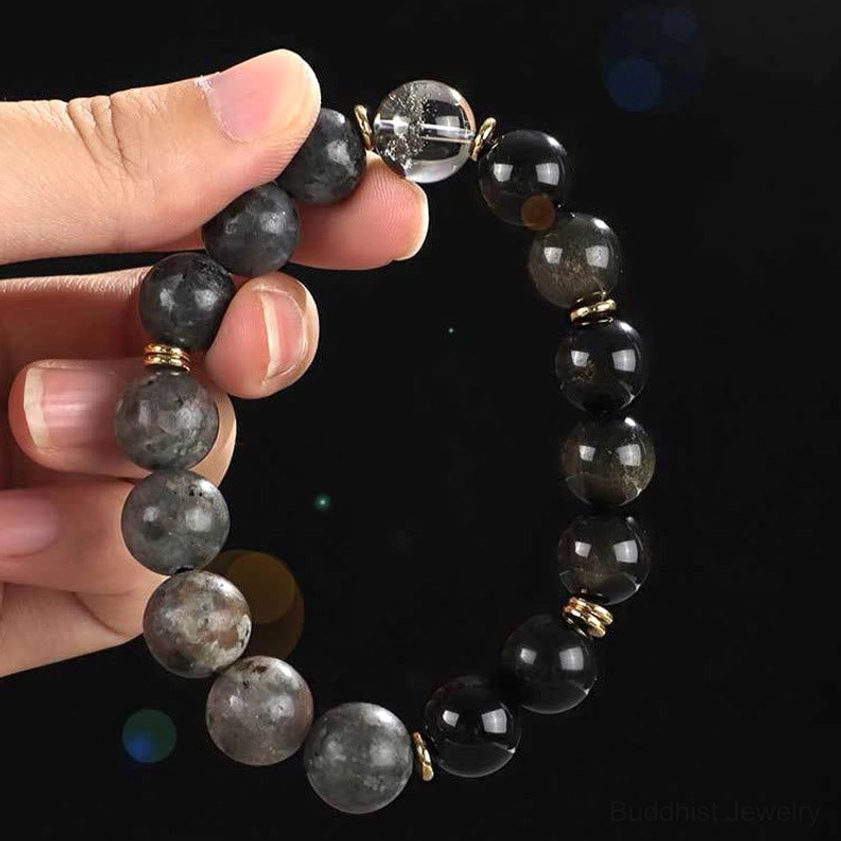 handheld beaded buddhist bracelet close-up showing clear quartz obsidian and silver metal accents