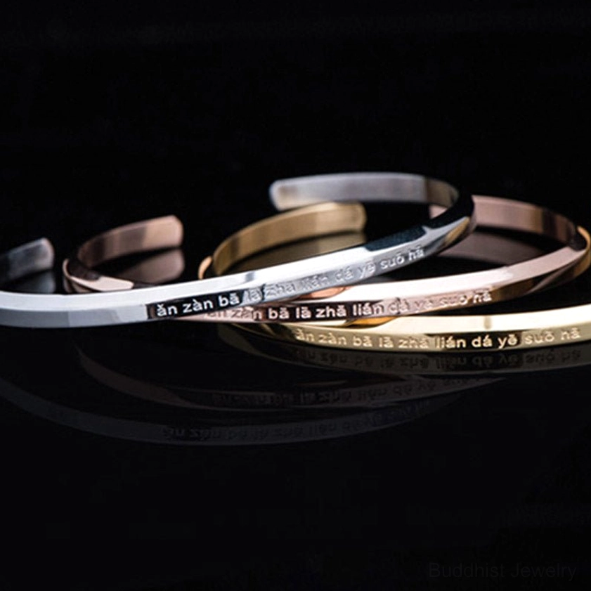 Stacked silver titanium steel om mani padme hum bracelets overhead view