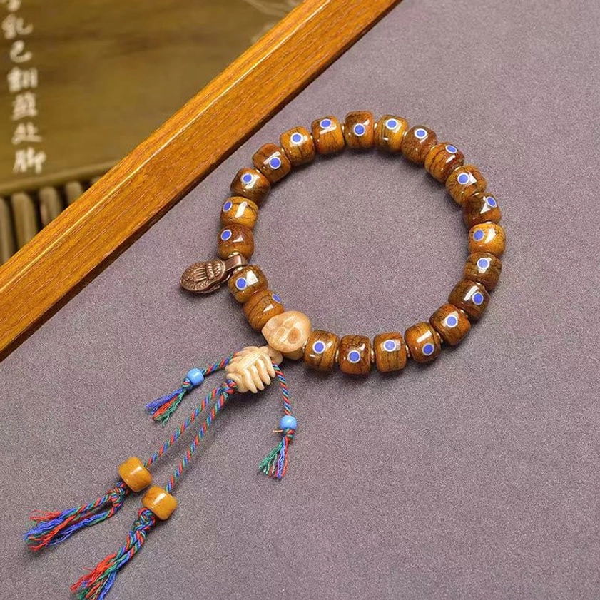 Skull skeleton bracelet with colorful woven tassels and wooden beads on display stand