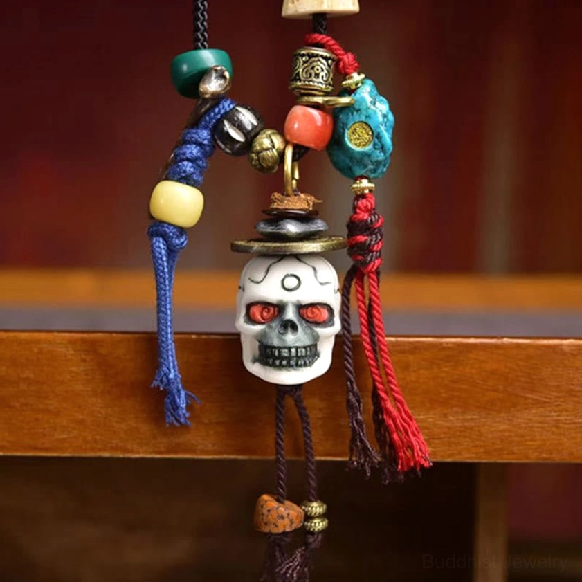 Close-up of white skull pendant with red eyes and blue red tassels - front detail view
