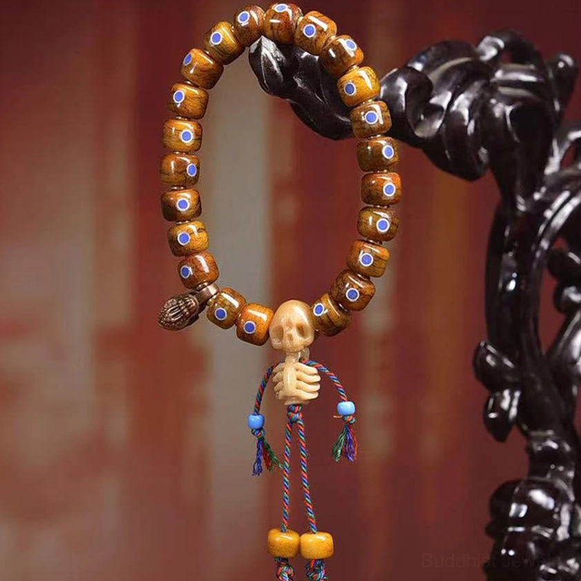 Bone skull focal bead bracelet with decorative tassels and metal skeleton charm pendant detail