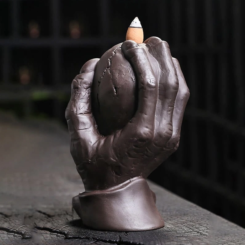 Purple clay skull backflow incense burner with protective ghost hand - front right three-quarter view showing realistic hand grip