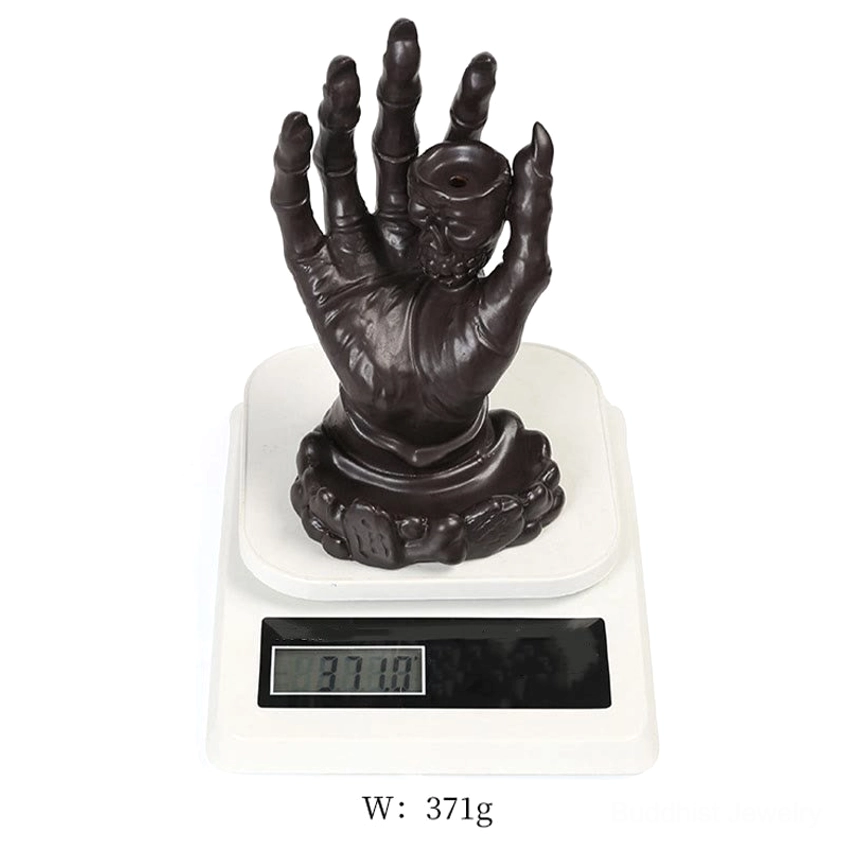 Brown ceramic skull hand incense holder displayed on digital scale for weight verification