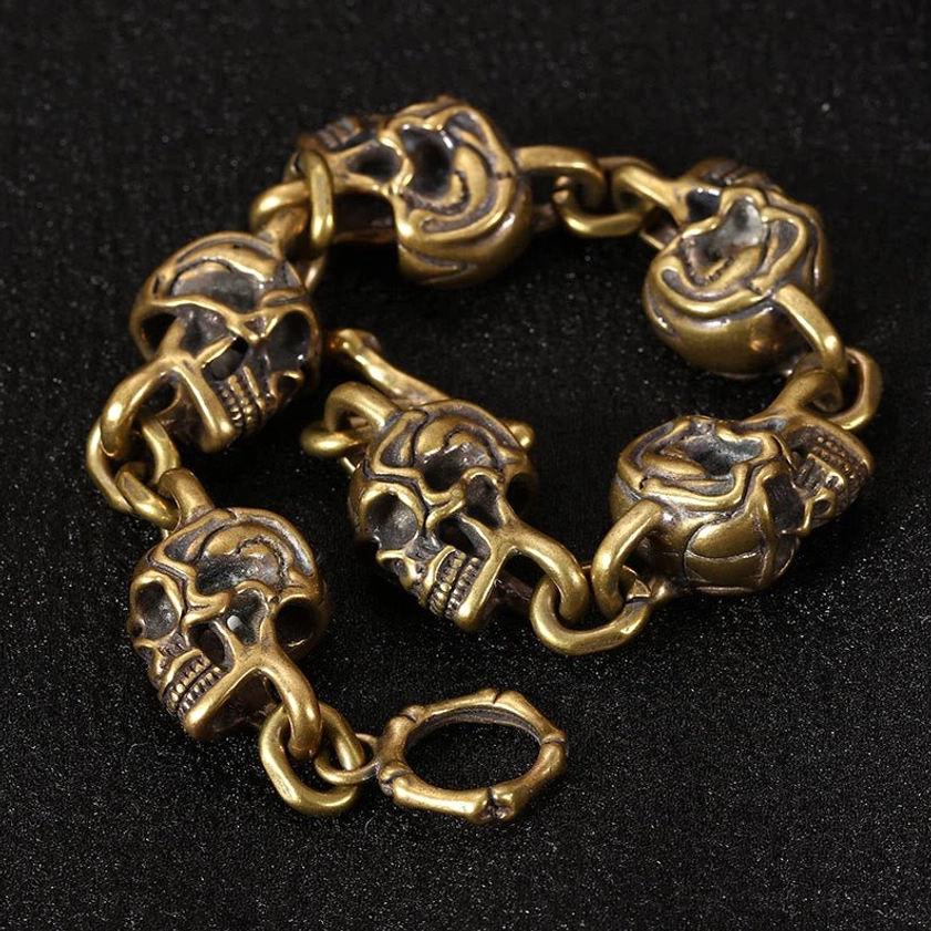 Vintage copper brass skull chain bracelet overhead view showing detailed 3D carved skulls arranged in circle on black background - impermanence mindfulness symbol