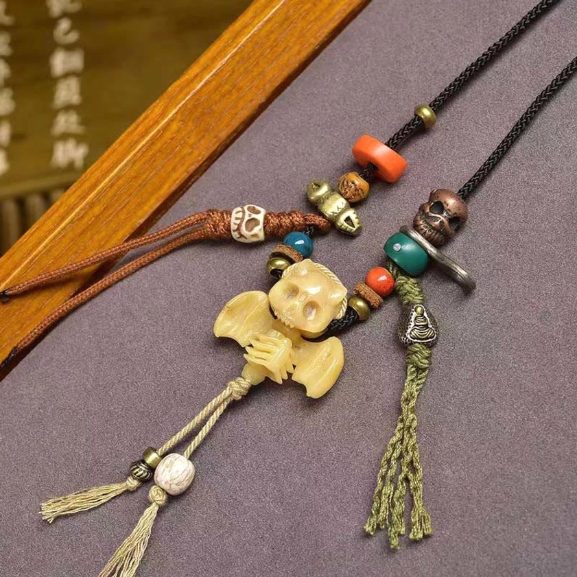 Bat wings skull pendant with brown braided rope orange beads and green tassel decoration