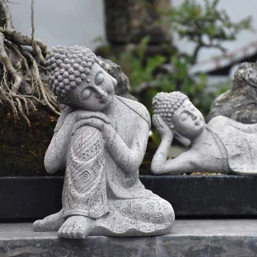 Reclining Buddha statue with peaceful resting posture displayed in garden setting with natural tree roots