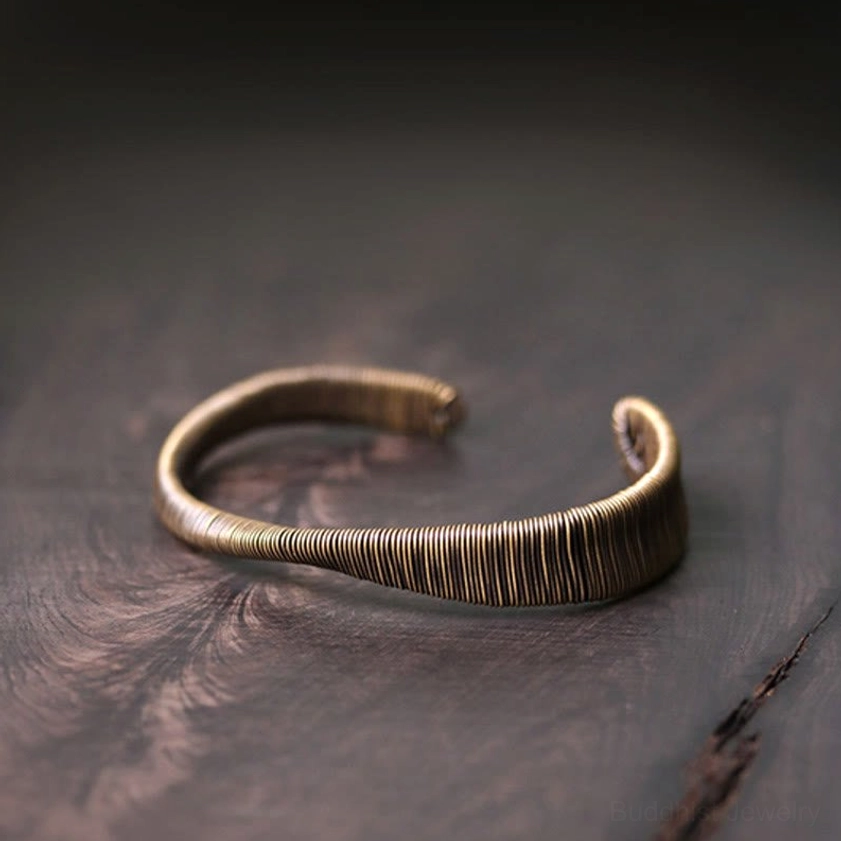 Slim open cuff bracelet top-down three-quarter view showing thin wrapped wire band with rounded open ends