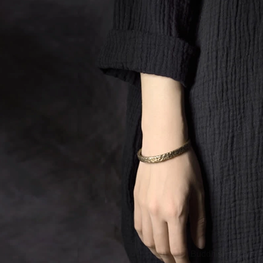 Slim hammered copper open cuff bracelet on wrist side view with black linen outfit showing elegant spiritual jewelry style