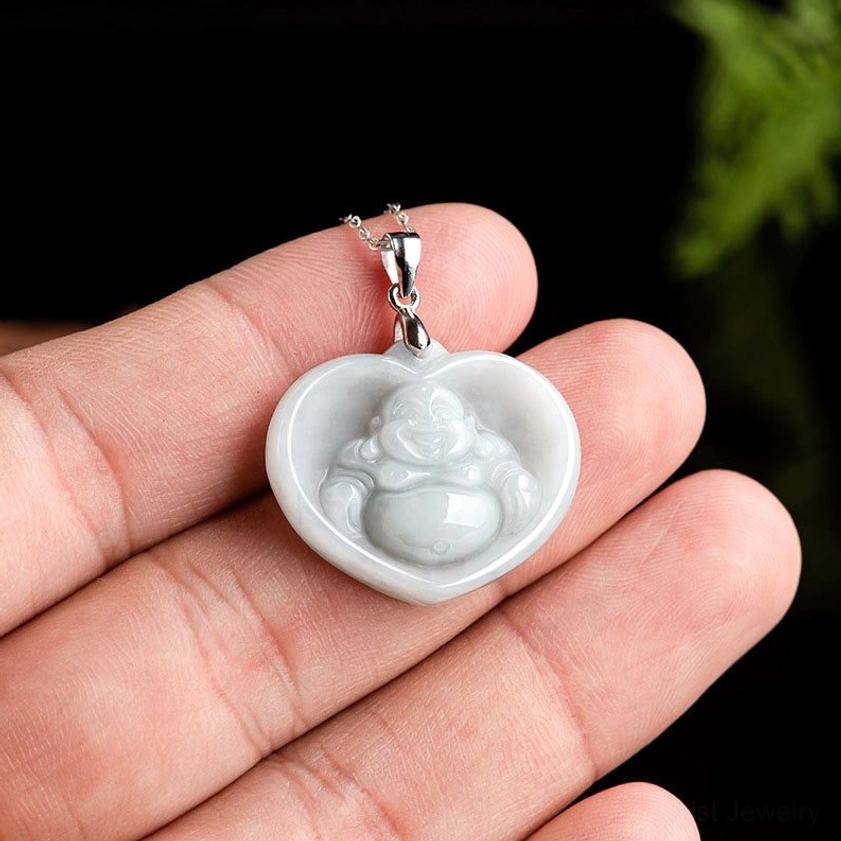 Dainty white jade laughing Buddha heart pendant held in hand showing delicate size and pale green-white color