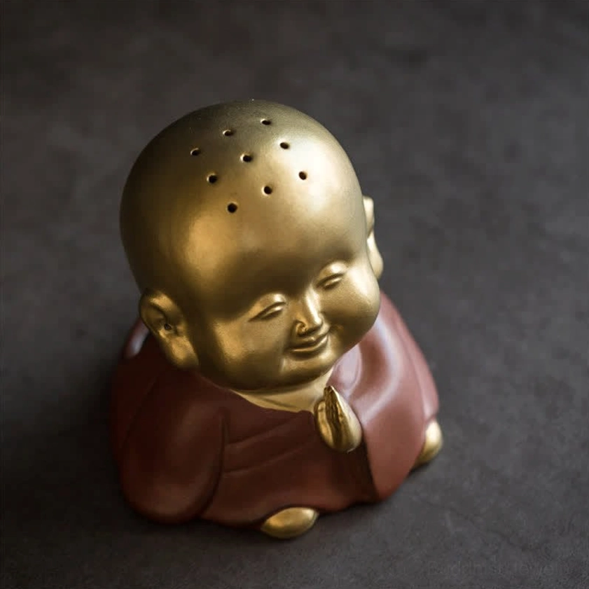 Smiling monk incense burner front full close-up against dark backdrop, detailed head perforations and reddish-brown ceramic finish