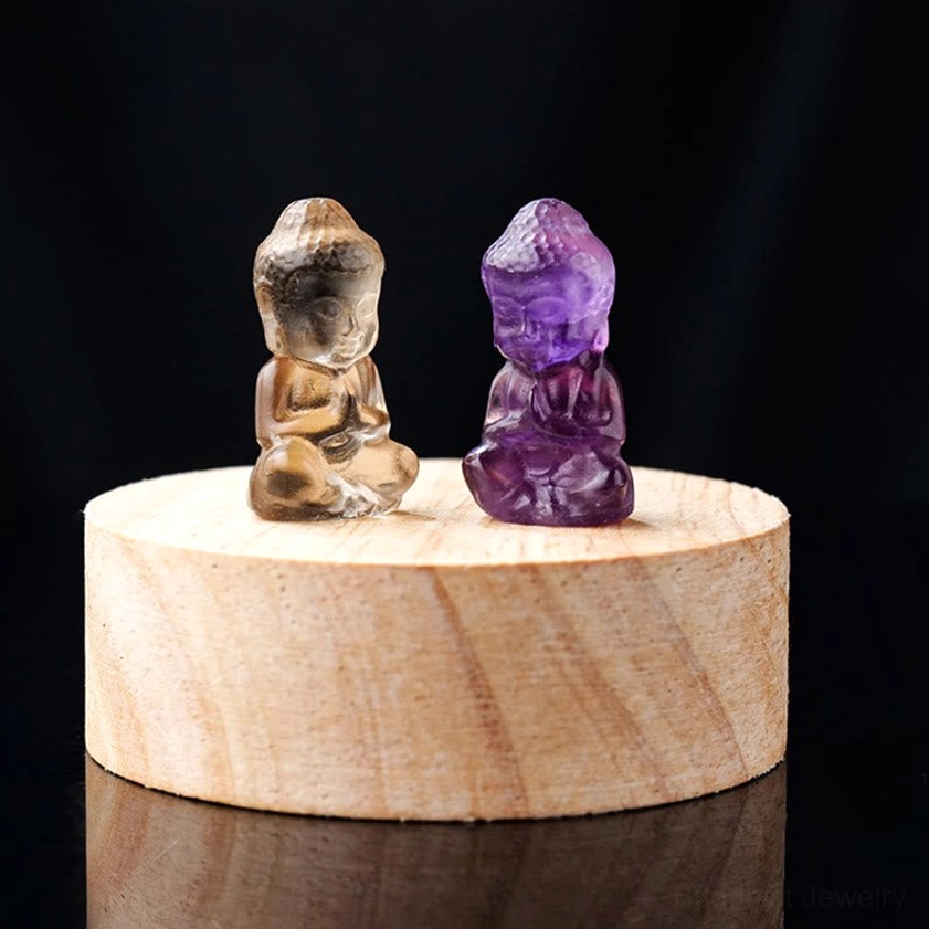 Smoky quartz and amethyst Buddha figurines comparison - brown and purple carved crystal Buddhas on wooden display base