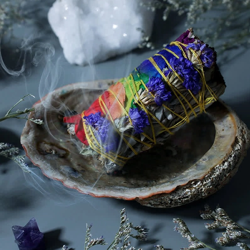Burning smudge stick in abalone shell with visible purifying smoke rising during cleansing ritual